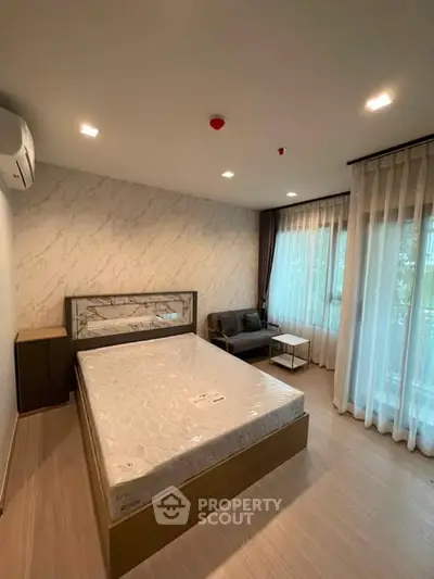 Modern bedroom with stylish decor and large windows offering natural light.