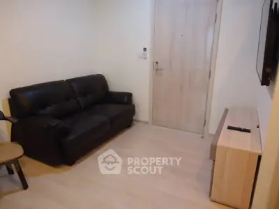 Cozy living room with leather sofa and wall-mounted TV in modern apartment.