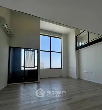 Spacious modern living room with high ceilings and large windows offering city views.