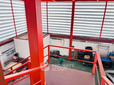 Industrial-style building interior with red metal beams and storage area.