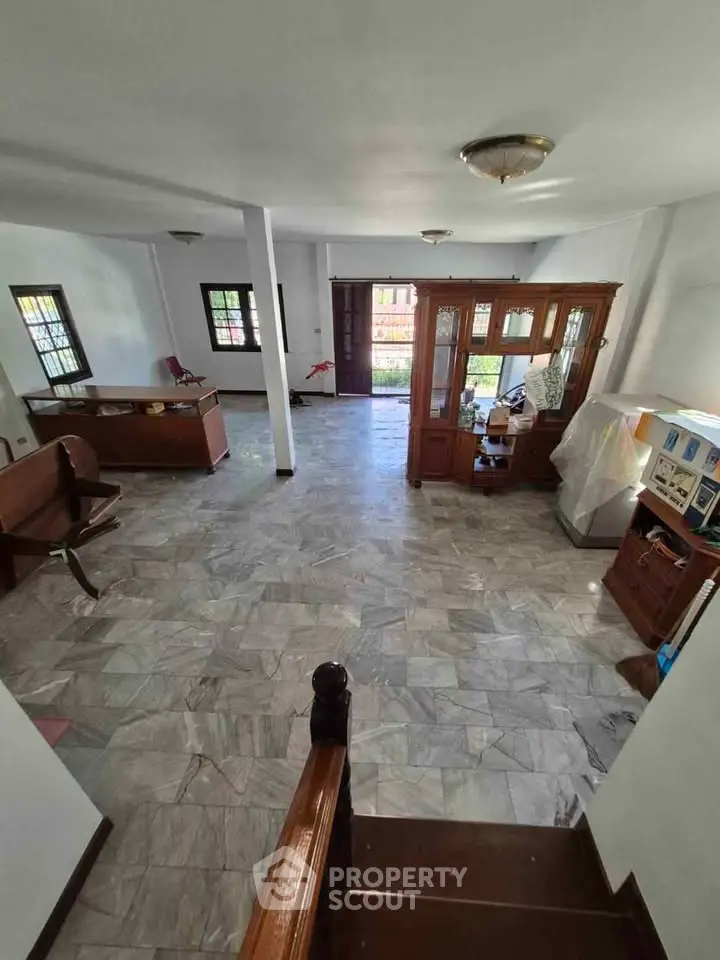 Spacious living room with marble flooring and wooden accents, ideal for family gatherings.