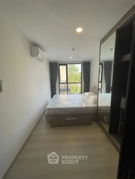 Modern bedroom with large window and mirrored wardrobe in a stylish apartment.