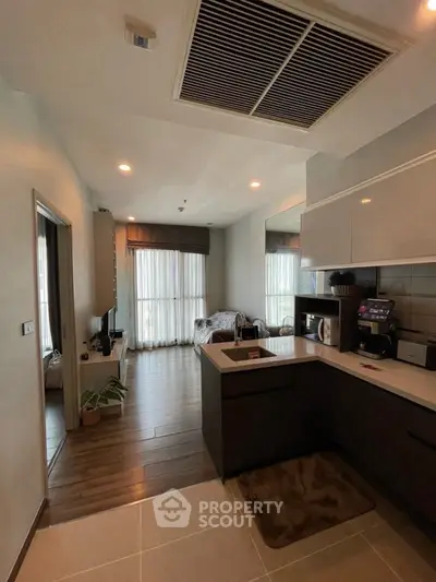 Modern kitchen with open layout and cozy living area, featuring sleek appliances and stylish decor.