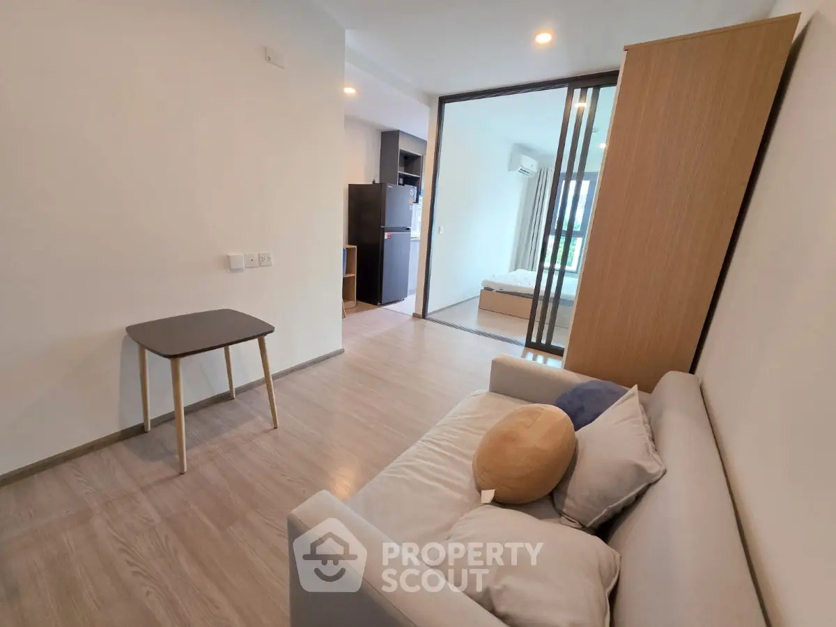 Modern apartment interior with cozy living room and bedroom view, featuring sleek furniture and open layout.