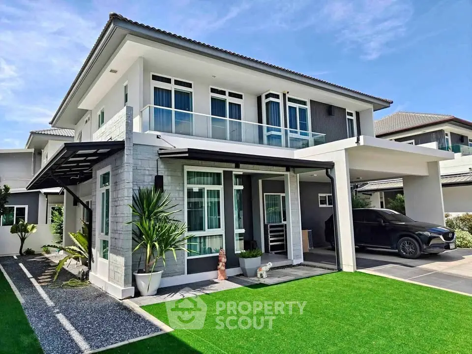 Modern two-story house with sleek design, lush green lawn, and spacious carport in a serene neighborhood.
