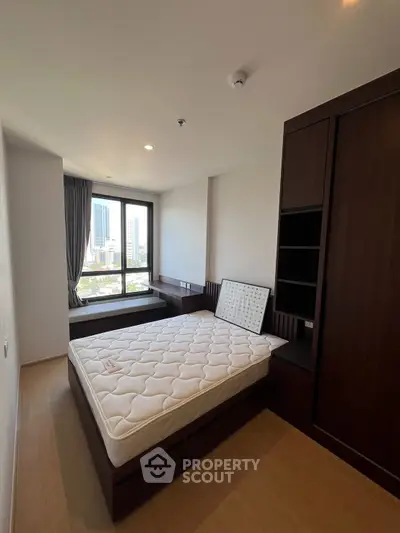 Modern bedroom with city view, featuring a comfortable bed and built-in wardrobe, ideal for urban living.