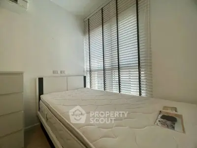 Cozy bedroom with large window and modern blinds, featuring a comfortable mattress and sleek dresser.