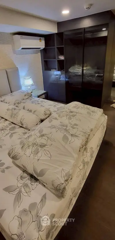 Cozy bedroom with floral bedding and modern wardrobe in stylish apartment