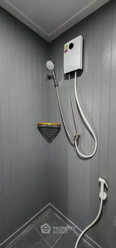 Modern bathroom with sleek shower and water heater in a stylish grey design.