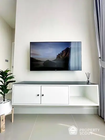 Modern living room with wall-mounted TV and sleek white cabinet