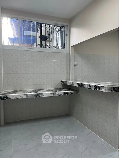 Modern kitchen with marble countertops and tiled walls, featuring a sleek design and ample workspace.