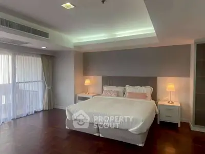 Spacious bedroom with elegant lighting and large windows in modern apartment.