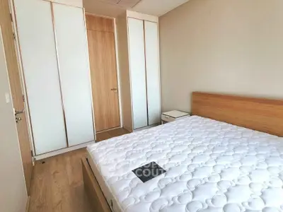 Modern bedroom with wooden furniture and built-in wardrobe, showcasing minimalist design and ample storage.