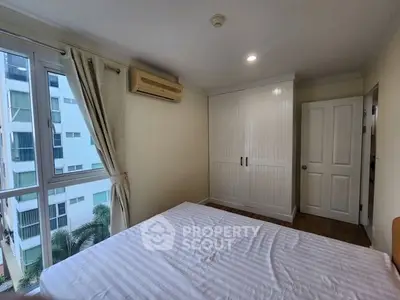 Bright bedroom with large window and built-in wardrobe in modern apartment