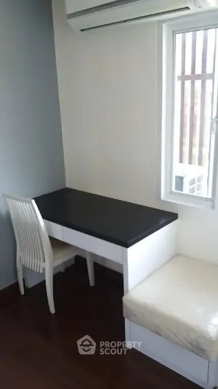 Cozy study nook with desk, chair, and window view in modern apartment.