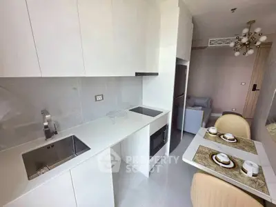 Modern kitchen with sleek white cabinetry and dining area in a stylish apartment.