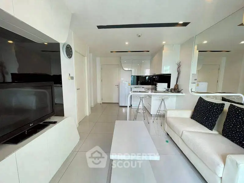 Modern living room with sleek white furniture and open kitchen layout