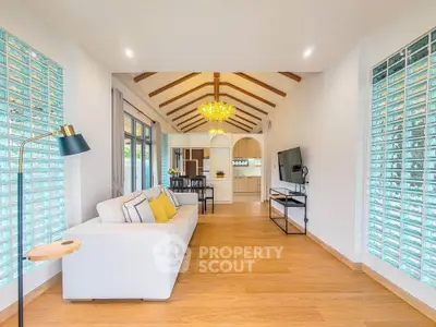 Spacious living room with modern decor and natural light, featuring a cozy sofa and stylish lighting.