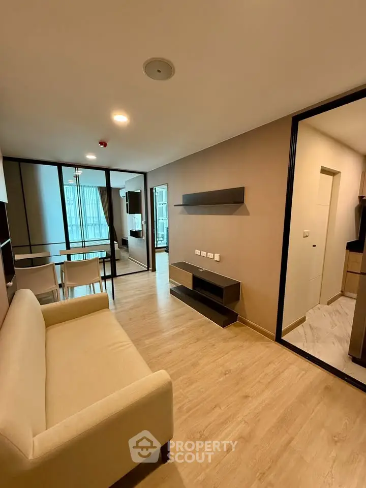 Modern living room with beige sofa, dining area, and open layout in a stylish apartment.