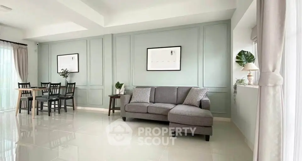 Elegant living room with modern decor and dining area, featuring stylish furniture and natural light.