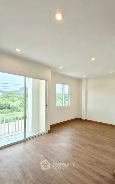Spacious living room with large windows and balcony access, offering abundant natural light and scenic views.