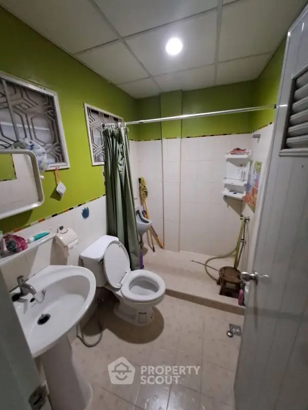 Cozy bathroom with green walls and modern fixtures, featuring a shower and toilet in a compact layout.