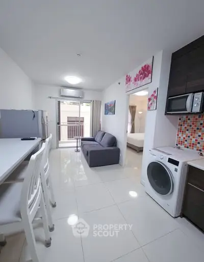 Modern open-plan living room with kitchen and balcony access in a stylish apartment.