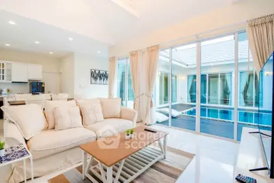 Spacious living room with pool view in modern home, featuring elegant decor and natural light.