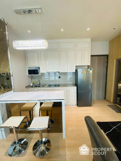 Modern kitchen with sleek design, marble countertop, and stylish bar stools in a contemporary apartment.