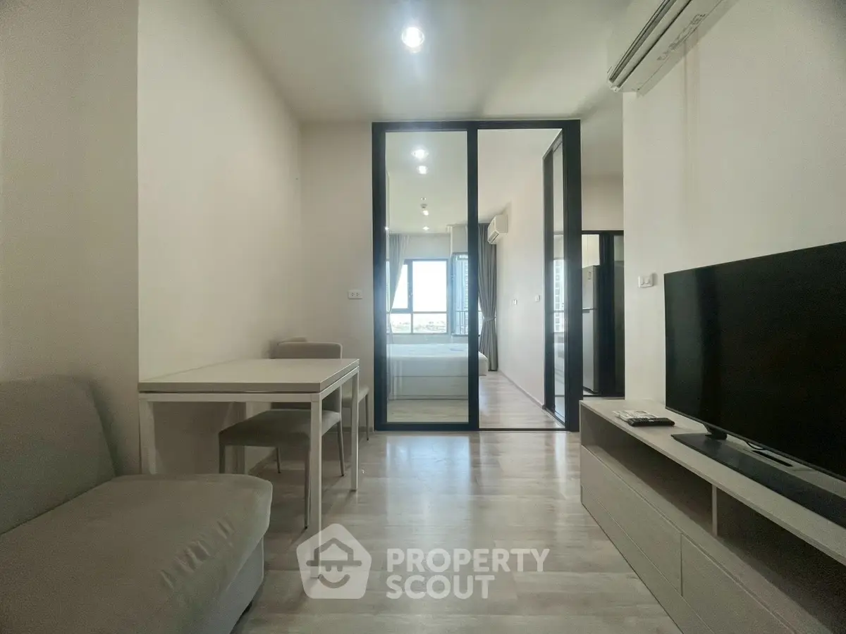 Modern living room with sleek furniture and glass partition, bright and airy ambiance.