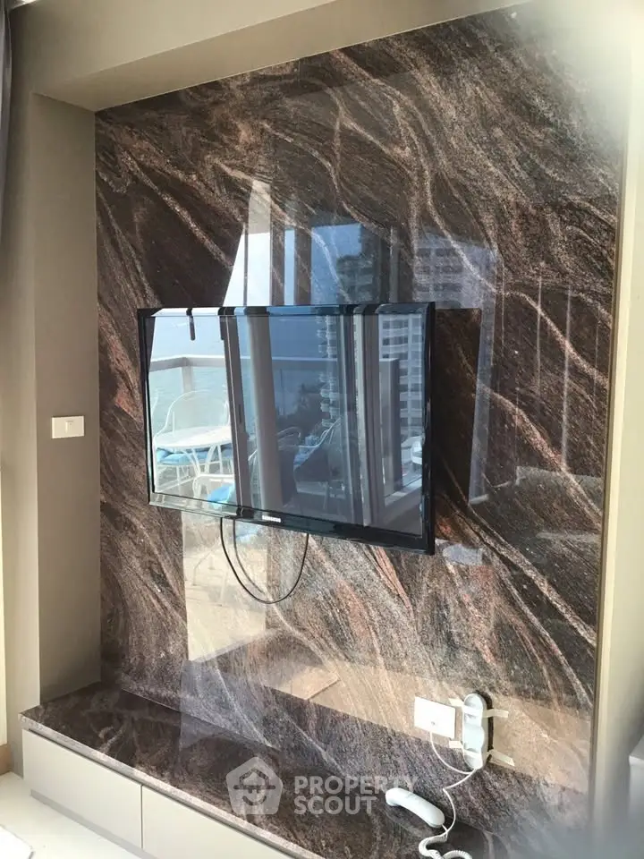 Luxurious living room with marble accent wall and mounted TV, offering a glimpse of a stunning city view.