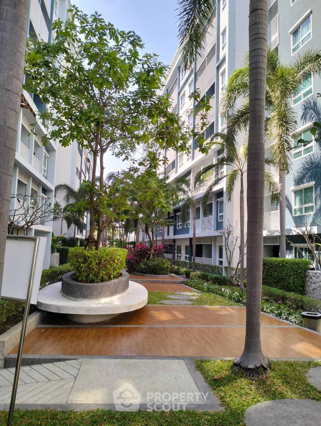 Modern residential building with lush garden and palm trees, offering serene outdoor space.