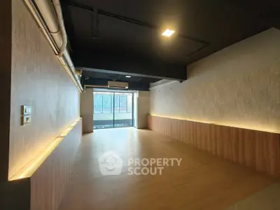 Spacious modern interior with wooden flooring and large window offering natural light.