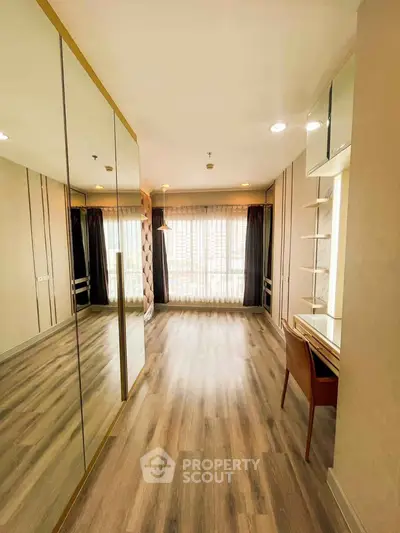Spacious bedroom with elegant wood flooring and large mirrored closet doors.