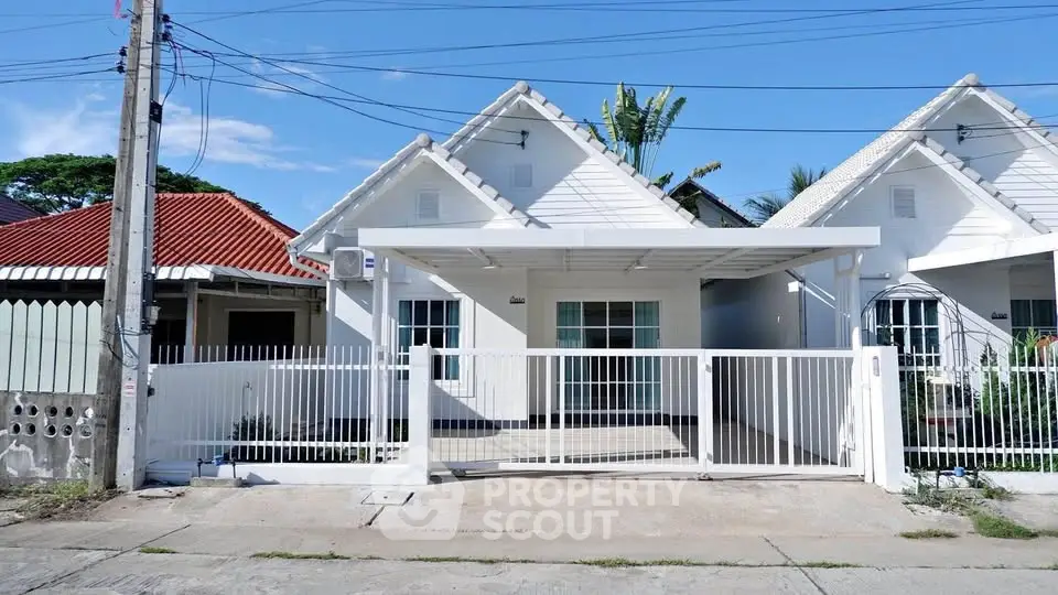 Charming white house with gabled roof and gated driveway in a serene neighborhood.