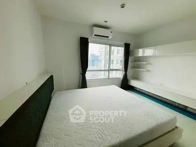 Spacious bedroom with city view and modern furnishings in high-rise apartment.