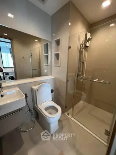 Modern bathroom with glass shower and sleek fixtures in contemporary apartment.