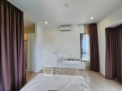 Spacious bedroom with modern decor and air conditioning, featuring elegant curtains and natural light.
