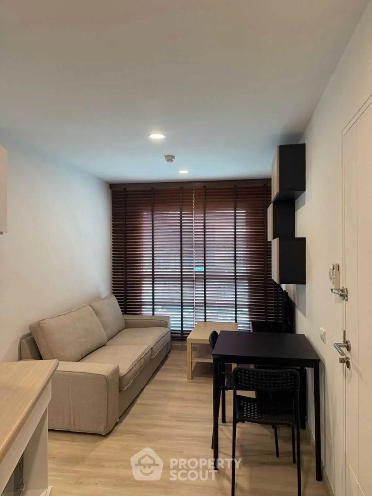 Modern living room with cozy sofa and dining area, featuring stylish blinds and wooden flooring.