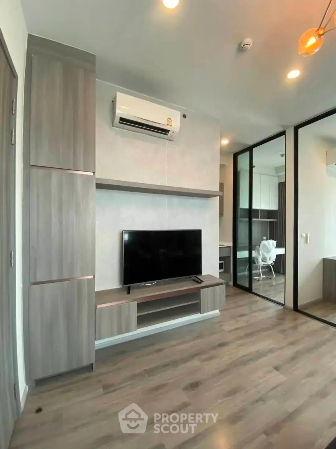 Modern living room with sleek design, featuring a mounted TV and air conditioning unit.