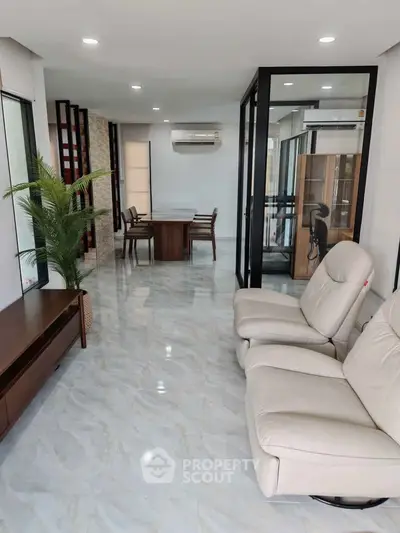 Spacious modern living room with sleek furniture and glass partitions, perfect for stylish urban living.