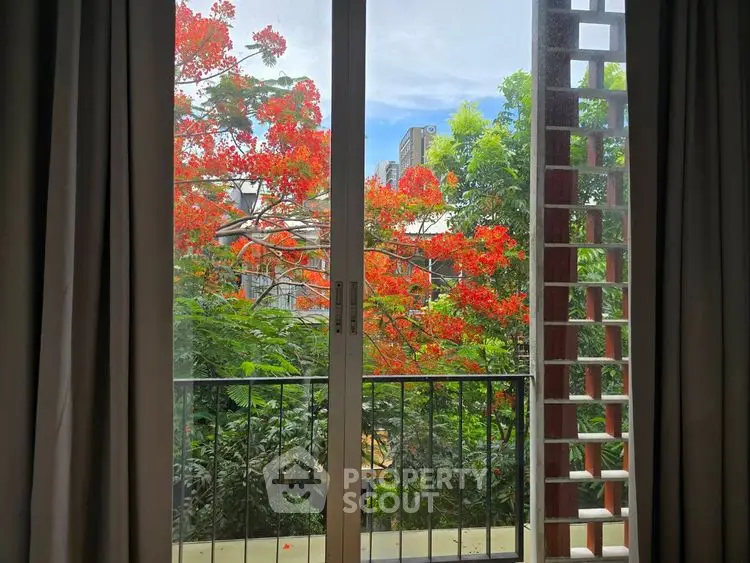 Charming balcony view with lush greenery and vibrant red flowers, perfect for nature lovers.