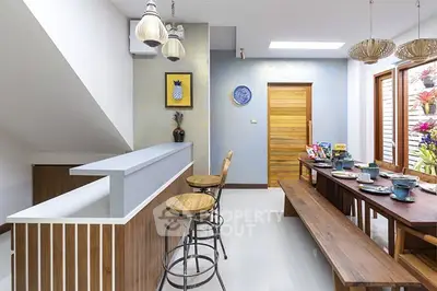 Modern kitchen with breakfast bar and dining table, featuring stylish lighting and decor.