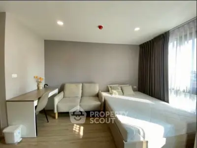 Modern bedroom with natural light, cozy sofa, and stylish decor in a contemporary apartment.