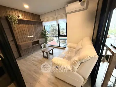 Modern living room with cozy white sofa and large windows offering city views.