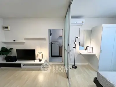 Modern studio apartment with sleek design, featuring a cozy living area and stylish bedroom separated by glass doors.
