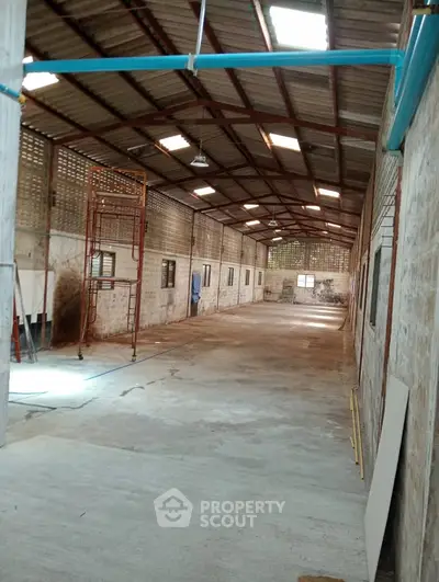 Spacious industrial warehouse with high ceilings and ample natural light, perfect for storage or manufacturing.