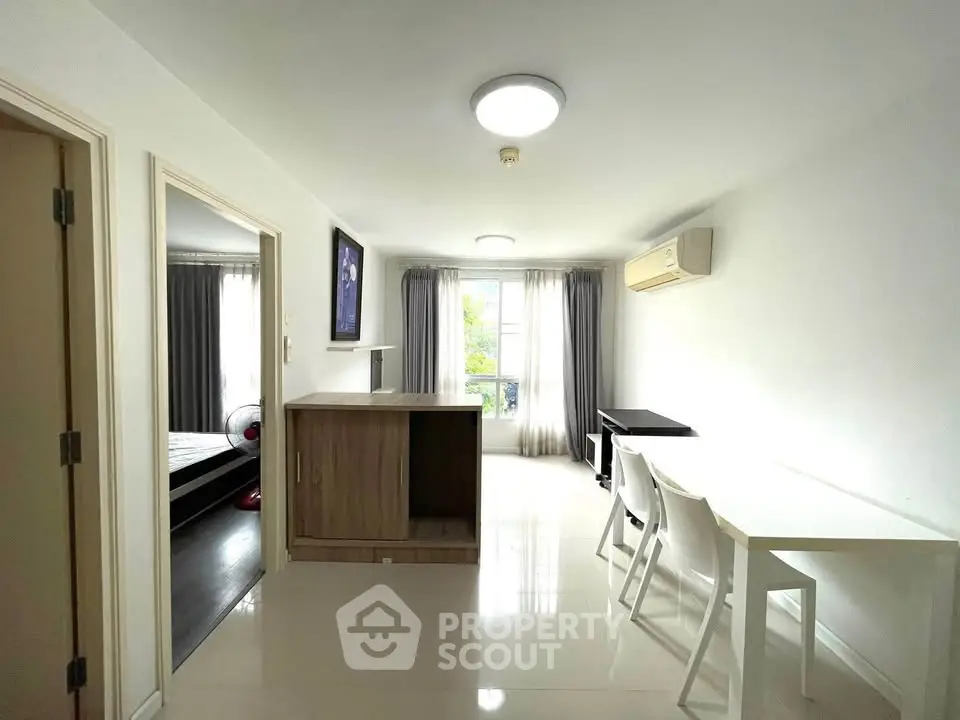 Bright modern living room with dining area and air conditioning, featuring sleek furniture and natural light.