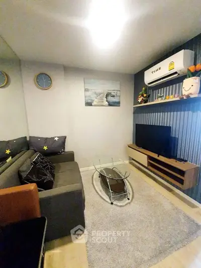 Cozy living room with modern decor, featuring a comfortable sofa, glass coffee table, and wall-mounted TV.