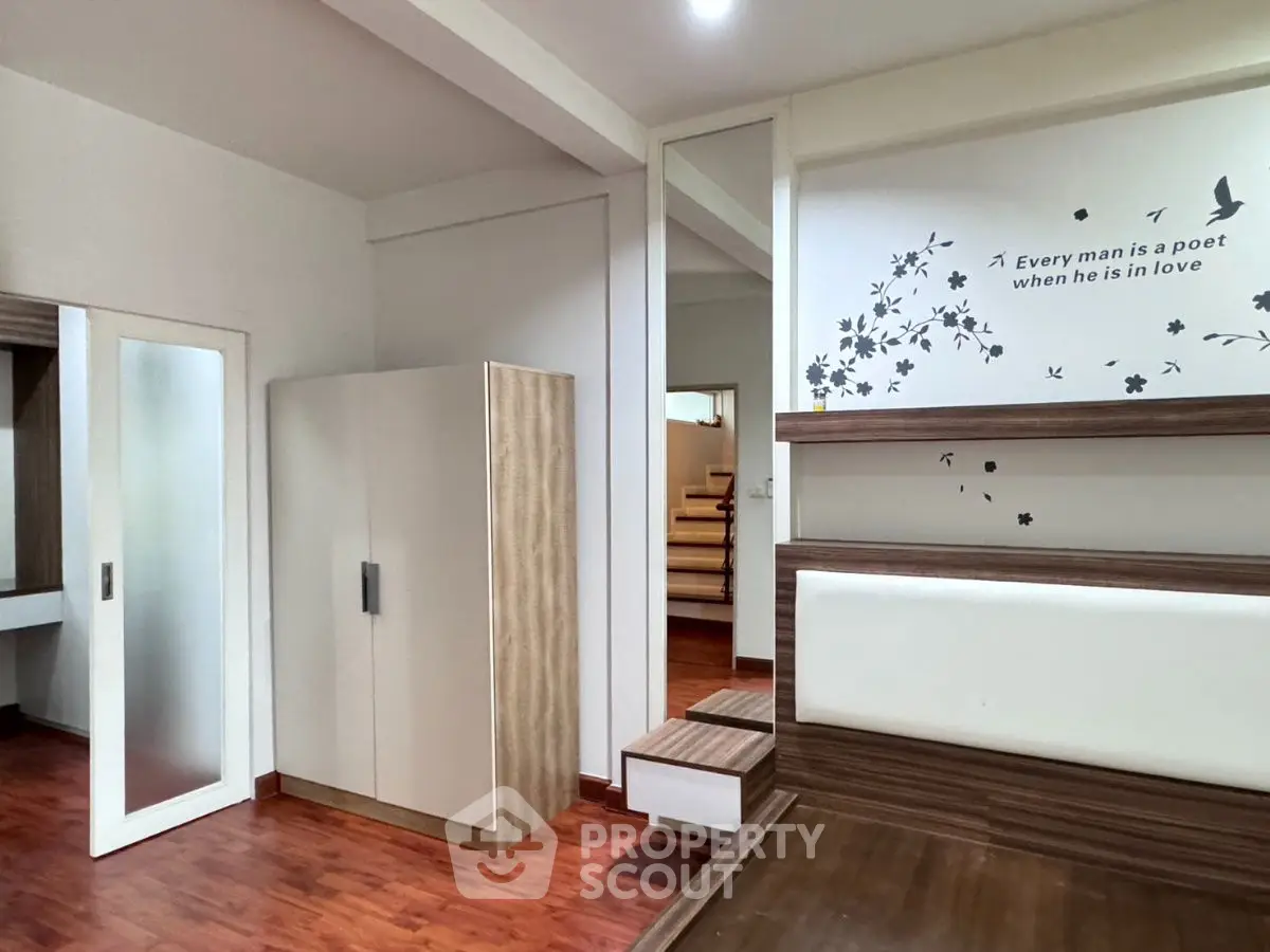 Modern bedroom with stylish decor and wooden flooring, featuring a poetic wall quote.